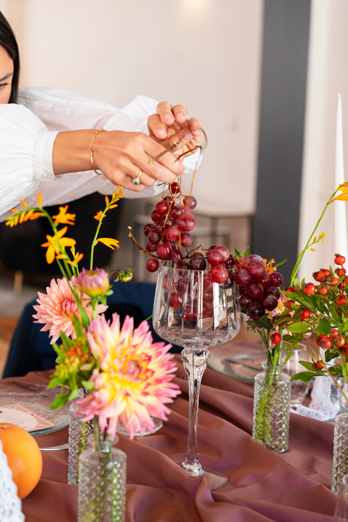 Une personne dispose une grappe de raisin sur la table fleurie du déjeuner Boulotte